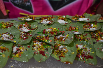 Banarasi pan and meetha pan garnished with betel nut and other ingredients displayed on a food stall for sale. Selective Focus