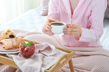 Young woman having tasty breakfast in bed