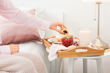 Young woman having tasty breakfast in bed