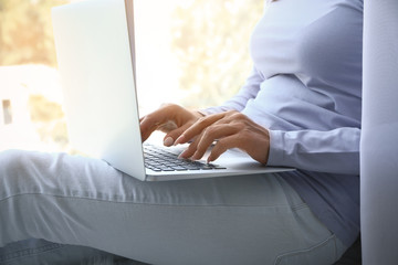 Young woman working on laptop near window
