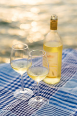Sunset view of two wine glasses and bottle of white wine on the background of Kotor bay, Montenegro.