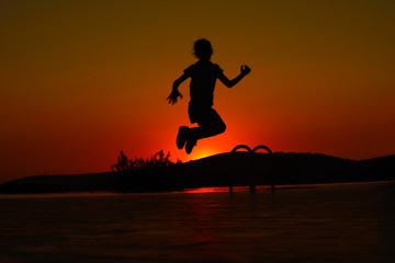 Fototapeta na wymiar silhouette of young a girl jumping on the beach at sunset