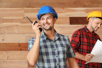 Fototapeta premium Portrait of male architect with portable radio transmitter and his team on wooden background