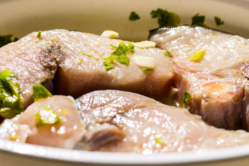 Marinated swordfish in a bowl with lemon, oil, garlic, parsley