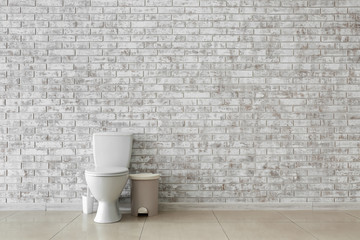 Fototapeta na wymiar Toilet bowl near light brick wall