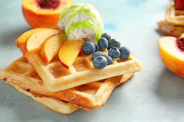 Tasty waffles with fruits, berries and ice-cream on color background