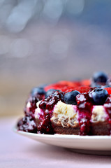 Detail of cheesecake tart with fresh strawberries, blueberries and cherry jam. Vertical photo.