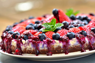 Tart with fresh strawberries, blueberries and cherry jam. Shallow depth of field