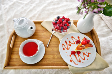 Tray with tasty breakfast on bed