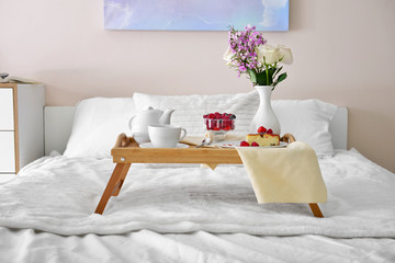 Fototapeta na wymiar Tray table with tasty breakfast on bed