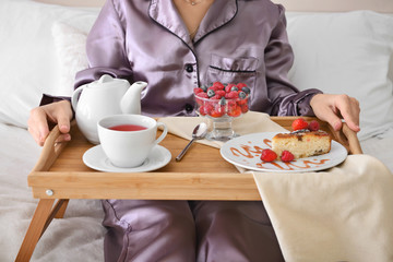 Obraz na płótnie Canvas Young woman having tasty breakfast in bed