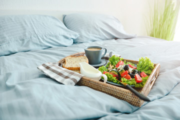 Tray with tasty breakfast on bed