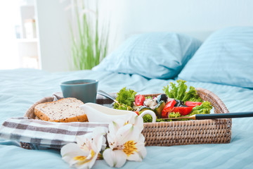 Tray with tasty breakfast on bed