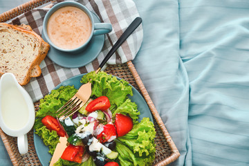 Tray with tasty breakfast on bed