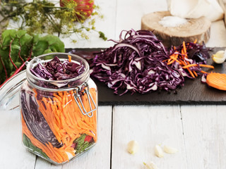Jar with chopped vegetables for fermentation. Carrots, dill, cabbage, garlic, salt, chard. Sliced vegetables on a black board. Organic vegetarian food. Close-up. Homemade healthy food.