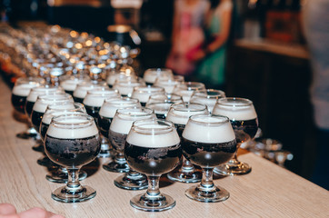 Glasses of dark beer on wooden bar counter. Bar on background