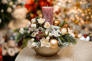 Gold colored vase with christmas decor composition of flowers, toys, fir-tree branches and one candle