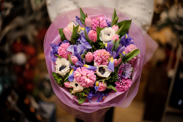 Girl holding a bouquet of pink and violet flowers with green leaves