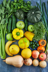 Vegetables and fruits in green-yellow tones on a blue background. View from above. Healthy eating concept.