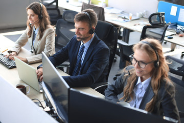 Portrait of call center worker accompanied by his team. Smiling customer support operator at work.