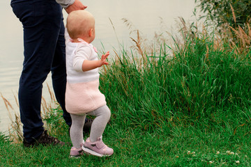 Dad teaches daughter to walk in nature. Father and daughter. First steps.