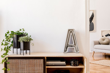 Modern scandinavian home interior with design wooden commode, plants in black pots, cement letter,...