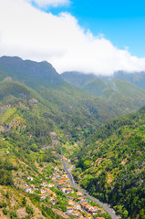 Naklejka na ściany i meble Amazing view of picturesque village Serra de Aqua in Madeira Island, Portugal. A small city in a valley surrounded by mountains covered.by green forest. Portuguese landscape. Tourist attraction