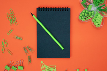 Educational composition, stationery. Green stationery and black notebook on a black background. Flat lay, top view, copy space.