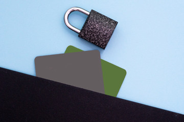 E-commers, banking, protection of personal information. Black and green bank credit, debit card and metal lock on a blue background. Flat lay, top view.