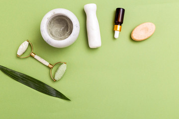 Face roller and skin care natural products on green background. Copy space