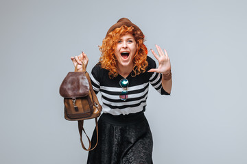 red head tourist girl with backpack on grey background