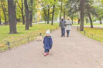 Obraz premium family mom dad and daughter walking in the Park with a dog