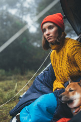 tourist traveler relaxation red shiba inu in camp tent on background blue foggy forest, closeup hiker woman with puppy in mist nature trip, friendship love concept