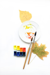 Happy autumn. Workplace with a plate, pens and watercolor palette, flat composition.