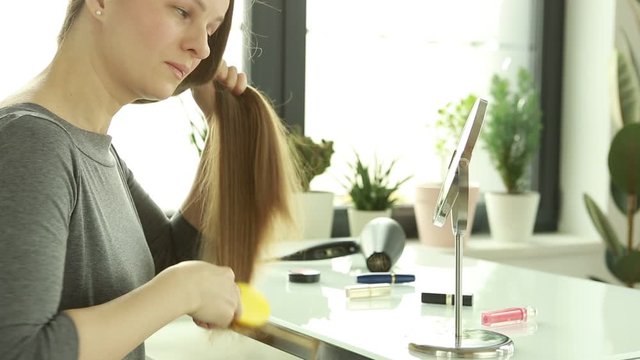 Hair loss. A woman is combing her hair.