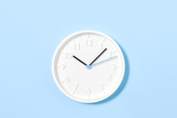 white wall clock on pastel blue background