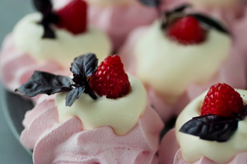 Raspberry meringues with fresh raspberries, basil and whipped cream on a gray plate.