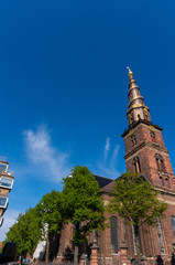 Fototapeta na wymiar Church of Our Saviour in Copenhagen, Denmark. The black and golden spire reaches a height of 90 metres and the external staircase turns four times counterclockwise around it