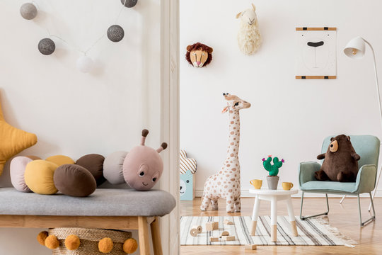 Modern and design scandinavian interior of kidroom with wooden bench, armachir, mock up poster frame, pillow, toys, teddy bear, plush toys and cute children's accessories. Stylish home decor. Template