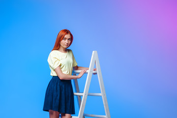 redhead girl climbs stairs on blue-pink background