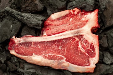 Raw t-bone steak with fresh herbs on a concrete or slate background, top view