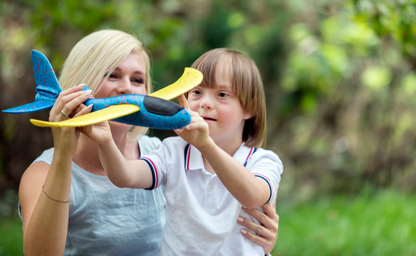 Caring mother and her sunny kid playing with a toy airplane on park