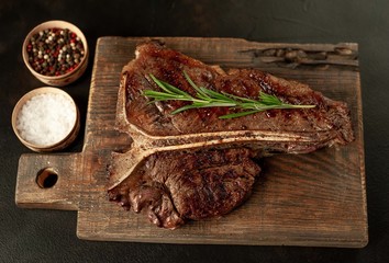 Grilled T-bone steak on a stone table. With rosemary and spices. 