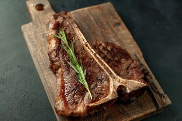 Grilled T-bone steak on a stone table. With rosemary and spices.