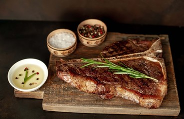 Grilled T-bone steak on a stone table. with a glass of red wine. With rosemary and spices.
