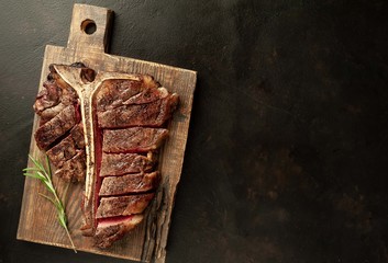 Grilled T-bone steak on a stone table. With rosemary and spices.