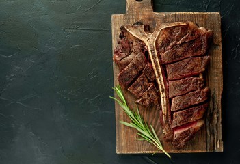 Grilled T-bone steak on a stone table. With rosemary and spices.
