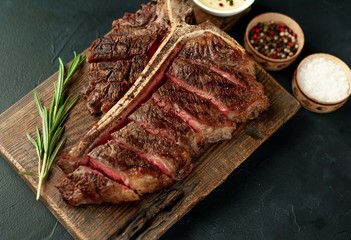 Grilled T-bone steak on a stone table. With rosemary and spices.