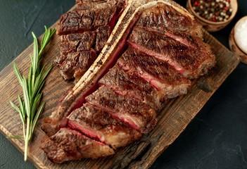 Grilled T-bone steak on a stone table. With rosemary and spices.