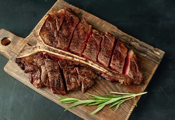 Grilled T-bone steak on a stone table. With rosemary and spices.